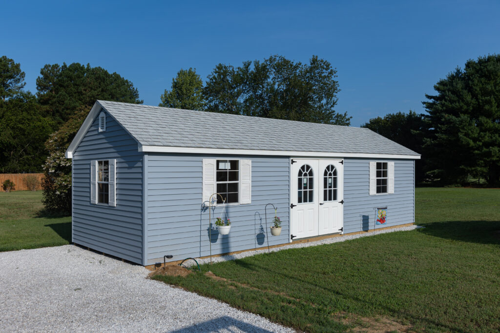 Blue and white storage shed installed on pad in backyard of Maryland residence