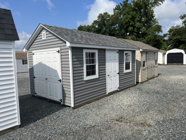 A grey storage shed with white trim