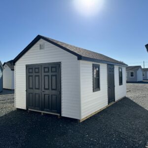 A white storage shed with black trim at The Olde Sale Barn